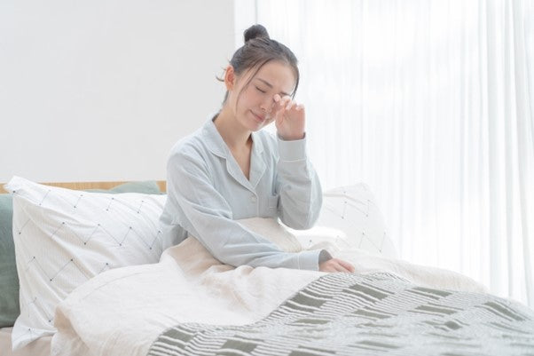 朝起きたけど眠そうでベッドから起き上がれない女性